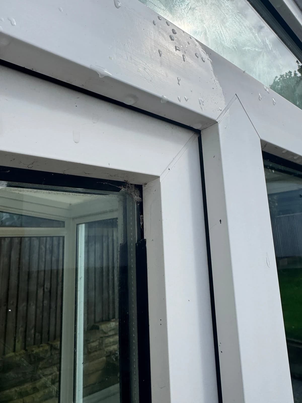A retracted glazing gasket leaving an open gap at a window corner.